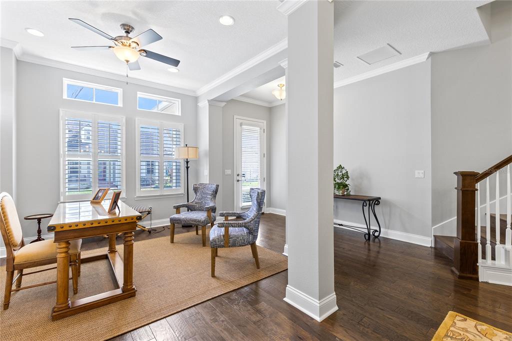 A home office features a wooden desk, two patterned armchairs, and dark hardwood floors — 8539 MARTINSON STREET, ORLANDO, FL
