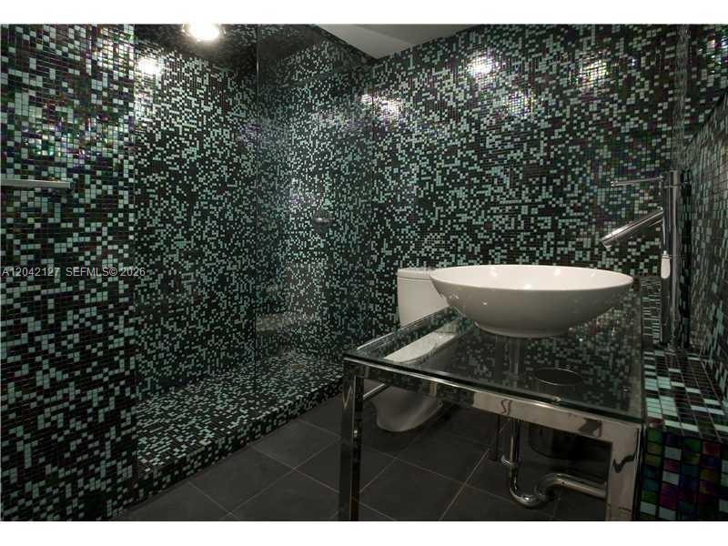 A bathroom features a glass vessel sink, chrome vanity, and walls covered in pixelated mosaic tiles — 1000 WEST AVE # 318, Miami Beach FL 33139, MIAMI BEACH, FL