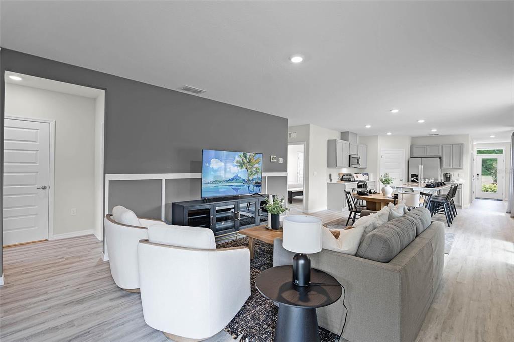 An open-concept living room features a gray accent wall, white wainscoting, and a modern kitchen — 4948 KAIA, WINTER HAVEN, FL