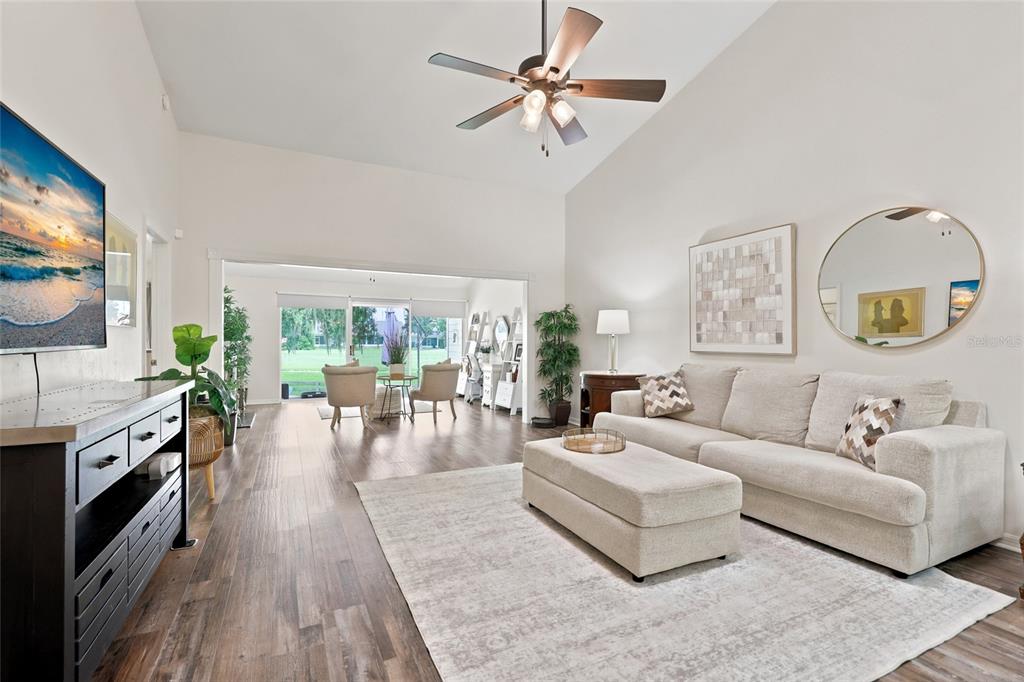 A living room features a vaulted ceiling, wood-look flooring, a sectional sofa, and sliding doors — 1022 NW 125TH DRIVE, NEWBERRY, FL