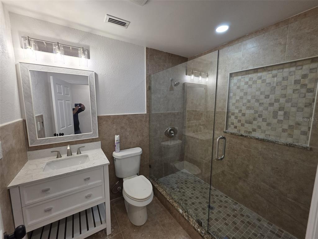A bathroom features a white vanity, a toilet, and a glass-enclosed walk-in tiled shower — 1401 PENNSYLVANIA AVENUE, CLEARWATER, FL