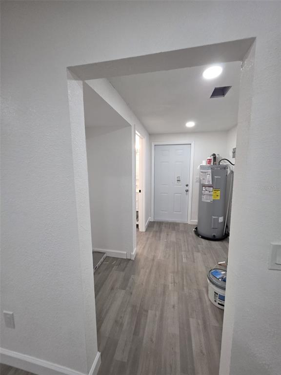 A utility room features light wood-look flooring, white walls, and a water heater — 1401 PENNSYLVANIA AVENUE, CLEARWATER, FL