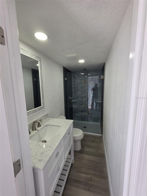 A bathroom features a white vanity with a marble countertop, a toilet, and a glass-enclosed shower — 1401 PENNSYLVANIA AVENUE, CLEARWATER, FL
