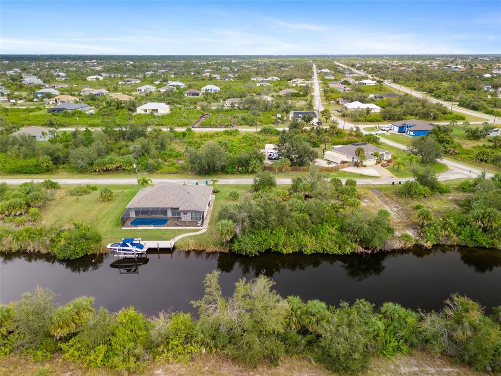 An aerial view shows a house with a pool and boat dock along a canal — 13902 BEGONIA CIRCLE, PORT CHARLOTTE, FL