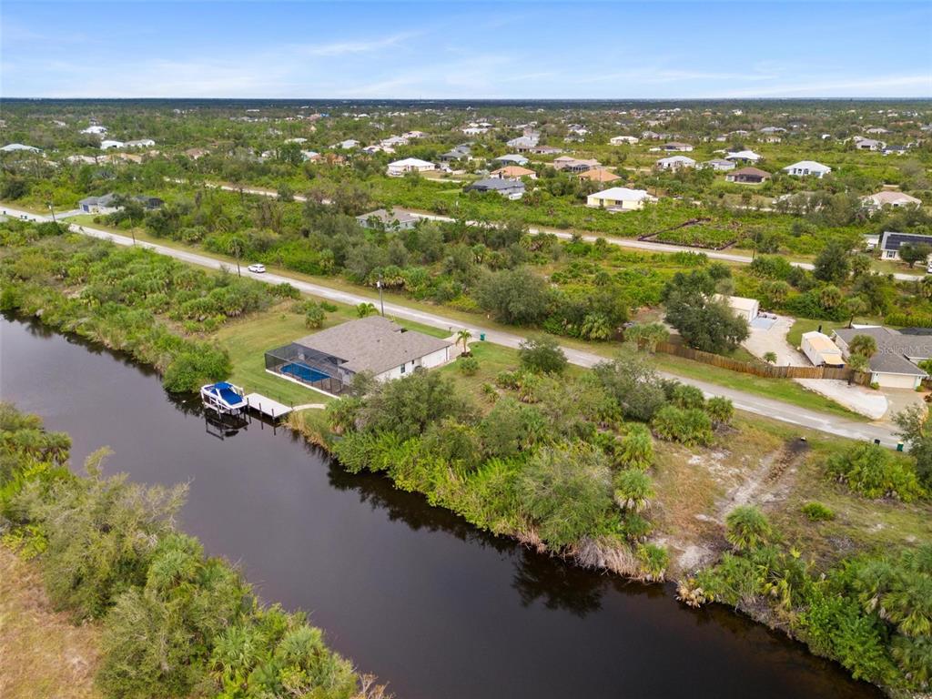 An aerial view shows a house with a pool cage and boat dock on a canal — 13902 BEGONIA CIRCLE, PORT CHARLOTTE, FL