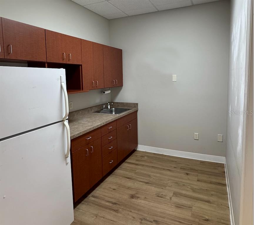 A small kitchenette features wood cabinets, a laminate countertop, a sink, and a white refrigerator — 910 OLD CAMP ROAD UNIT 154, THE VILLAGES, FL
