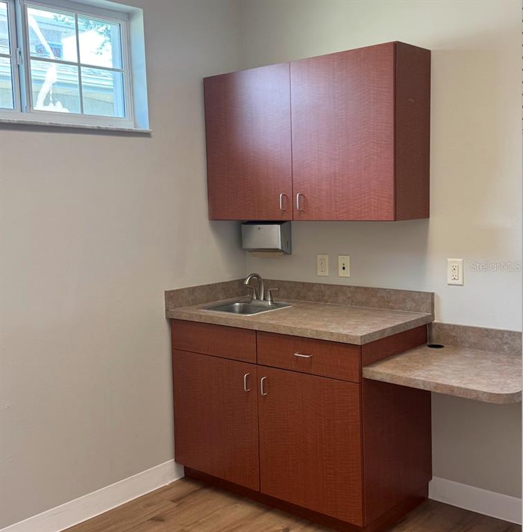 A small kitchenette features wood-look cabinets, a stainless steel sink, and a laminate countertop — 910 OLD CAMP ROAD UNIT 154, THE VILLAGES, FL