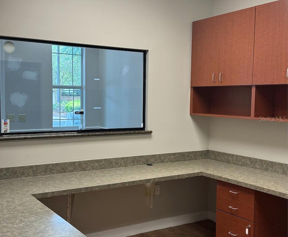 An office space features a built-in desk with laminate countertops, wood cabinets, and a large window — 910 OLD CAMP ROAD UNIT 154, THE VILLAGES, FL