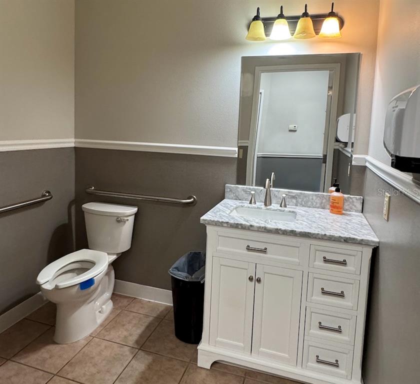A bathroom features a white vanity with a marble countertop, a toilet, and grab bars — 910 OLD CAMP ROAD UNIT 154, THE VILLAGES, FL