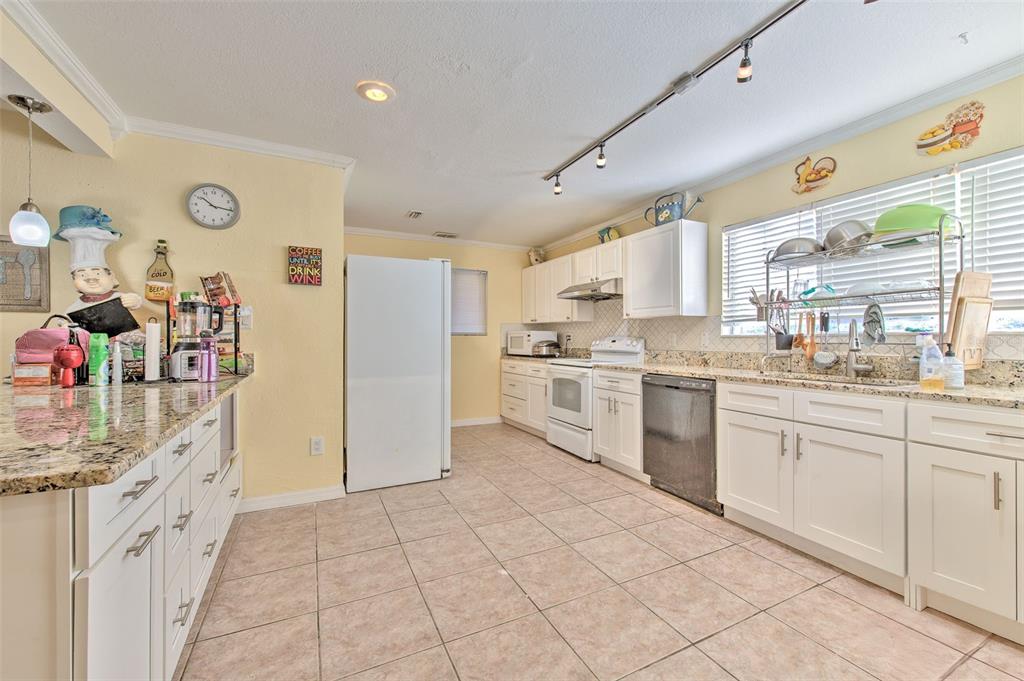 A kitchen features white cabinets, granite countertops, tile flooring, and a white refrigerator — 5415 MILES BOULEVARD, PORT RICHEY, FL