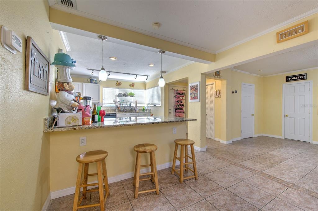 A kitchen with a granite breakfast bar, wooden stools, and yellow walls — 5415 MILES BOULEVARD, PORT RICHEY, FL