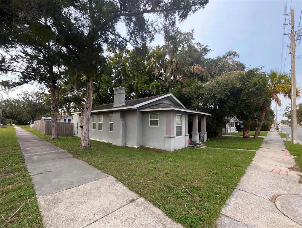 A gray, single-story house with a chimney and a front porch sits on a corner lot — 1712 W MAIN STREET, LEESBURG, FL
