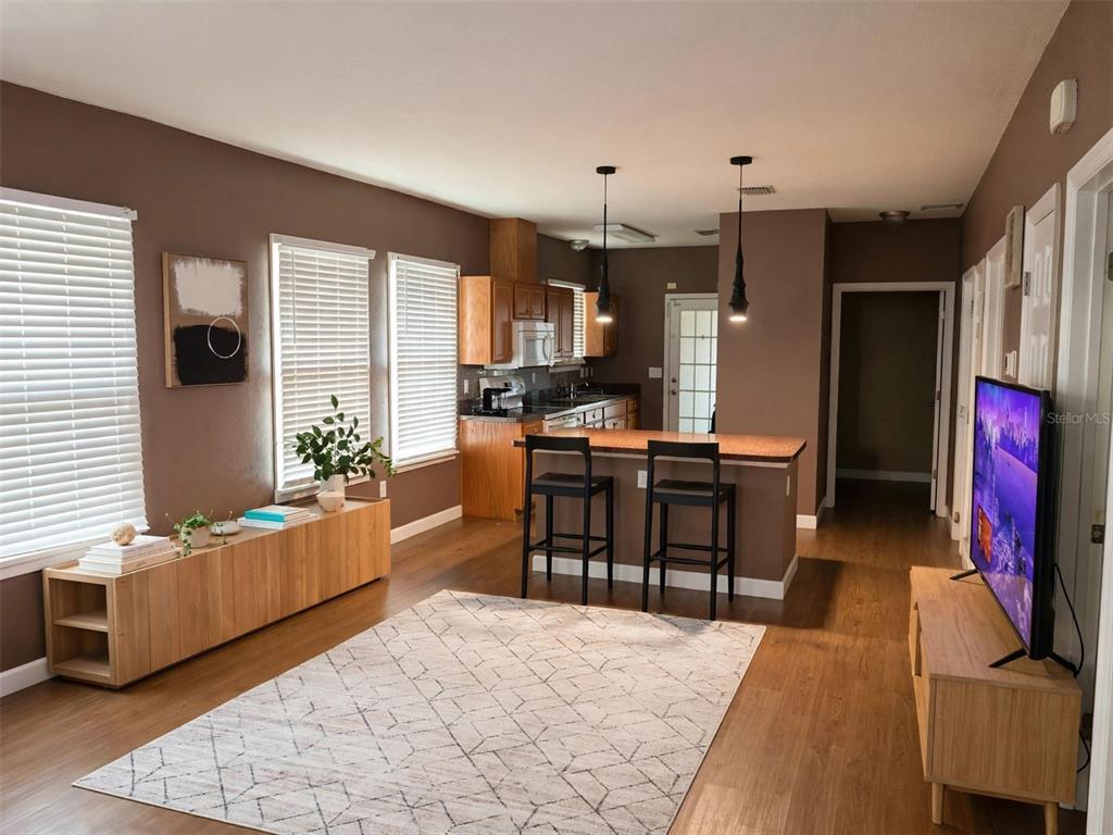 A living room with wood-look flooring, a kitchen island with bar stools, and brown walls — 1712 W MAIN STREET, LEESBURG, FL