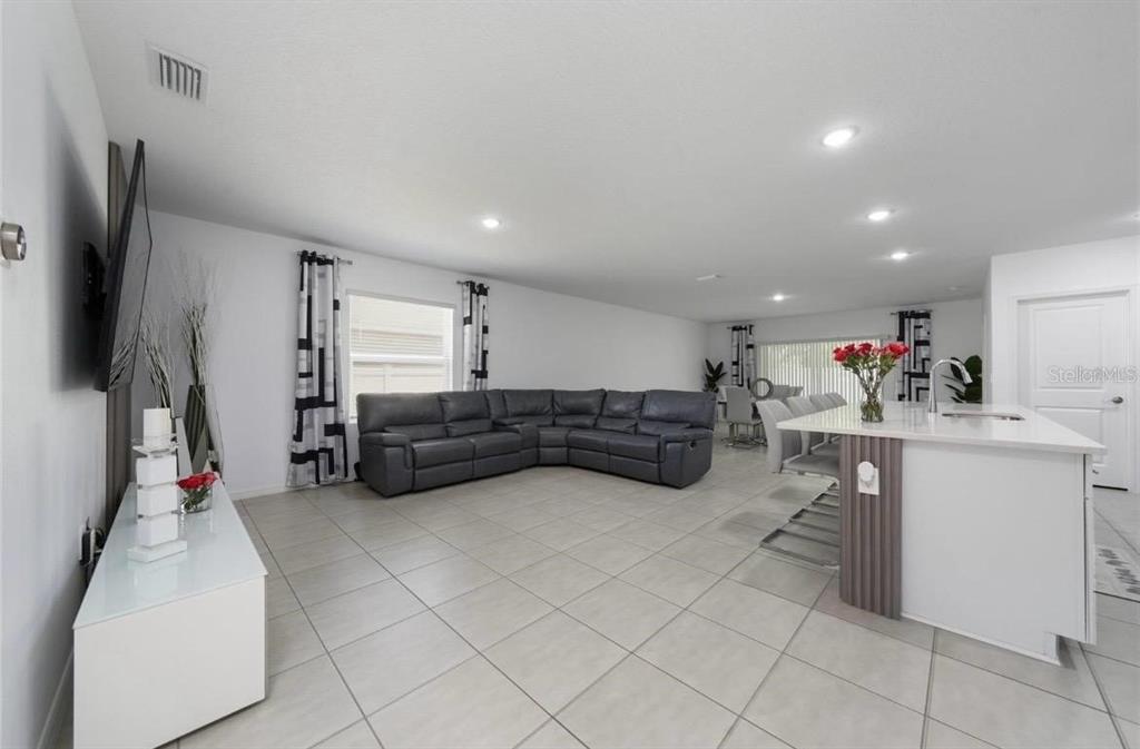 An open-concept living room and kitchen featuring a grey sectional sofa and white island — 1383 LEVY BEND DRIVE, KISSIMMEE, FL