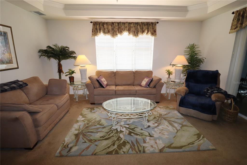 A living room features a beige sofa set, a glass coffee table, and a patterned rug — 255 W END DRIVE UNIT 2210, PUNTA GORDA, FL