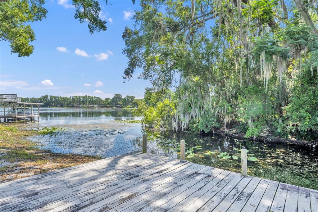 A wooden dock overlooks a lake with a boat lift and trees draped in moss — 1009 LAKE BELL DRIVE, WINTER PARK, FL