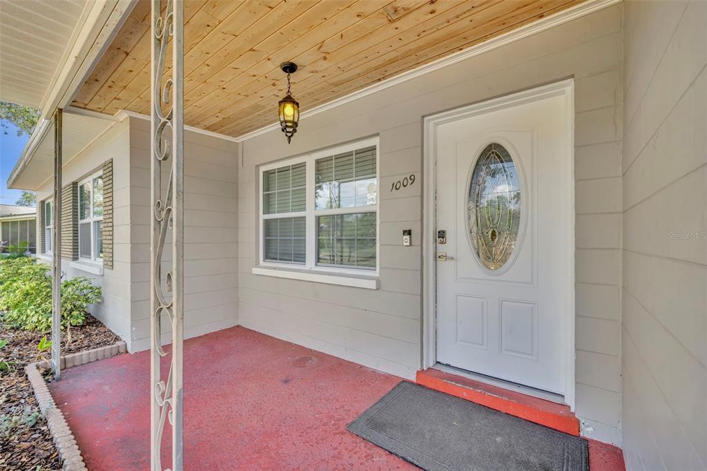 The exterior view shows a covered front porch with a wood-paneled ceiling and white door — 1009 LAKE BELL DRIVE, WINTER PARK, FL
