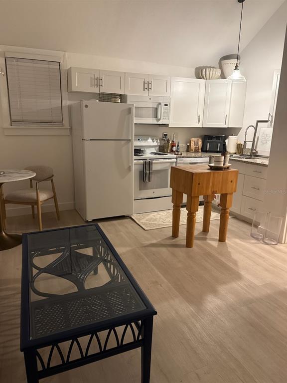 A kitchen features white cabinets, a refrigerator, a stove, and a wooden butcher block island — 305 MARY AVENUE, NEW SMYRNA BEACH, FL
