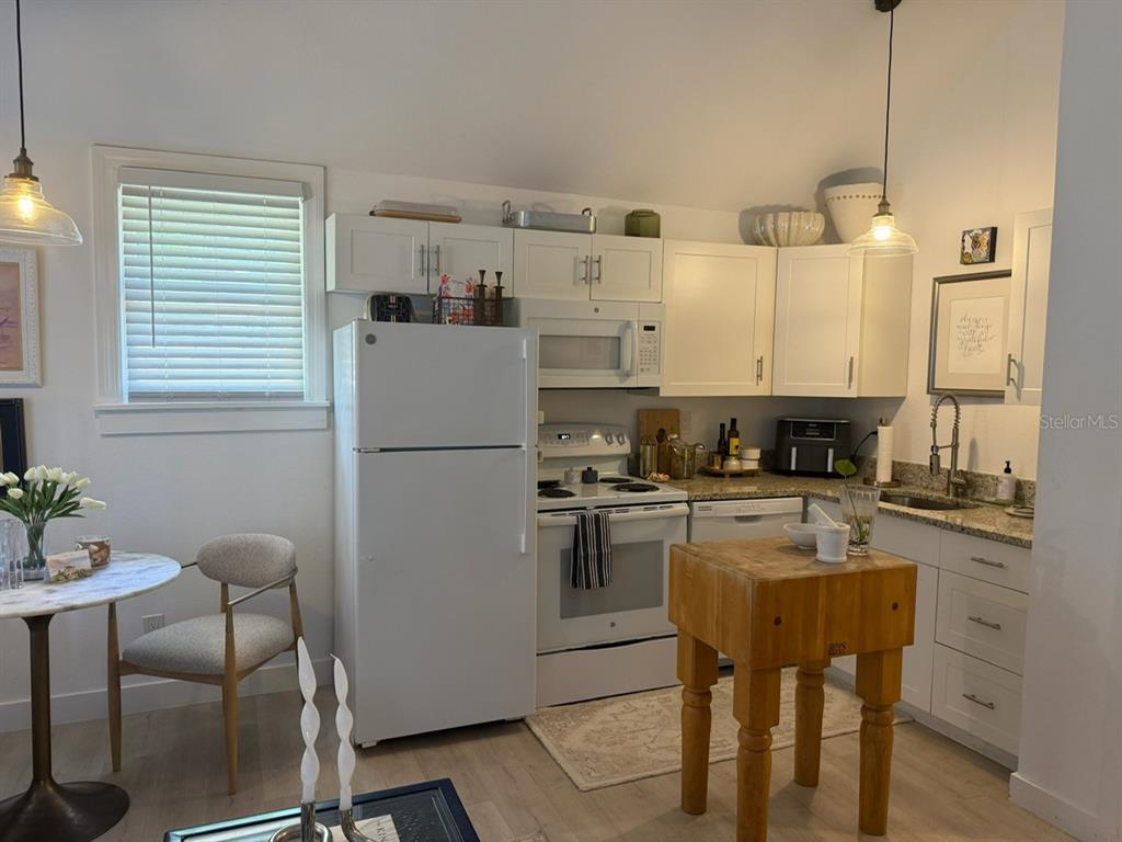 A kitchen features white cabinets, a white refrigerator, a stove, and a wooden butcher block island — 305 MARY AVENUE, NEW SMYRNA BEACH, FL