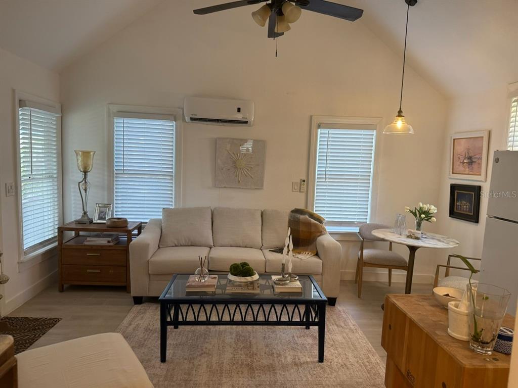 A living room with a sofa, coffee table, dining area, and vaulted ceiling with a fan — 305 MARY AVENUE, NEW SMYRNA BEACH, FL
