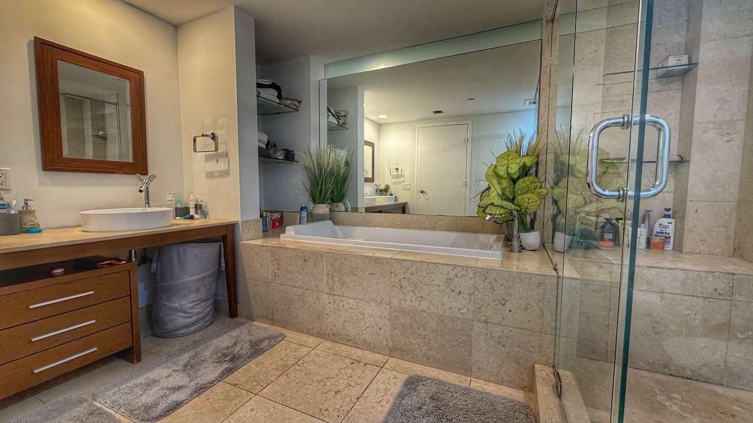 A bathroom features a stone-tiled soaking tub, a glass-enclosed shower, and a wooden vanity — 485 Brickell Avenue # 3608, Miami FL 33131, MIAMI, FL