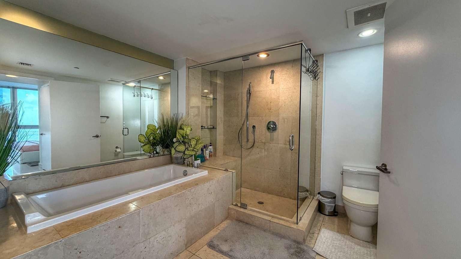 A bathroom features a soaking tub, a glass-enclosed shower, and a toilet with stone tiling — 485 Brickell Avenue # 3608, Miami FL 33131, MIAMI, FL