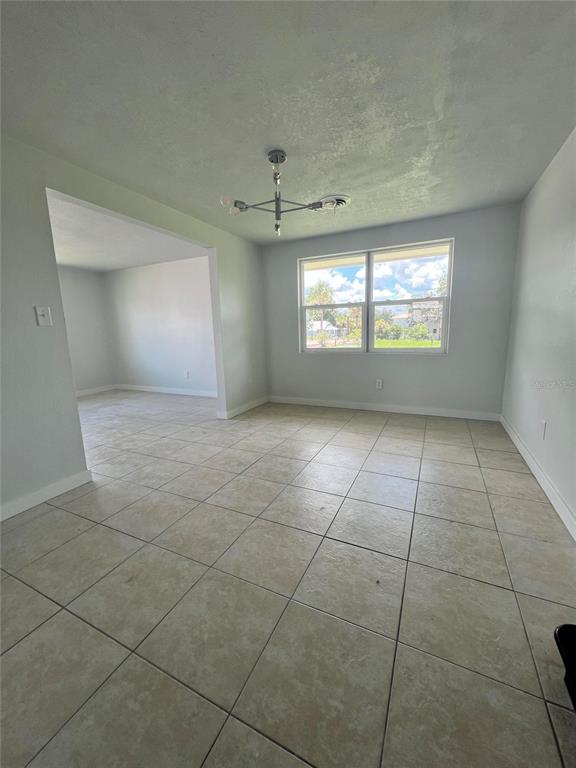 A dining area with light-colored tile flooring, a modern chandelier, and a view of outdoors — 744 LEMON AVENUE, SEBRING, FL