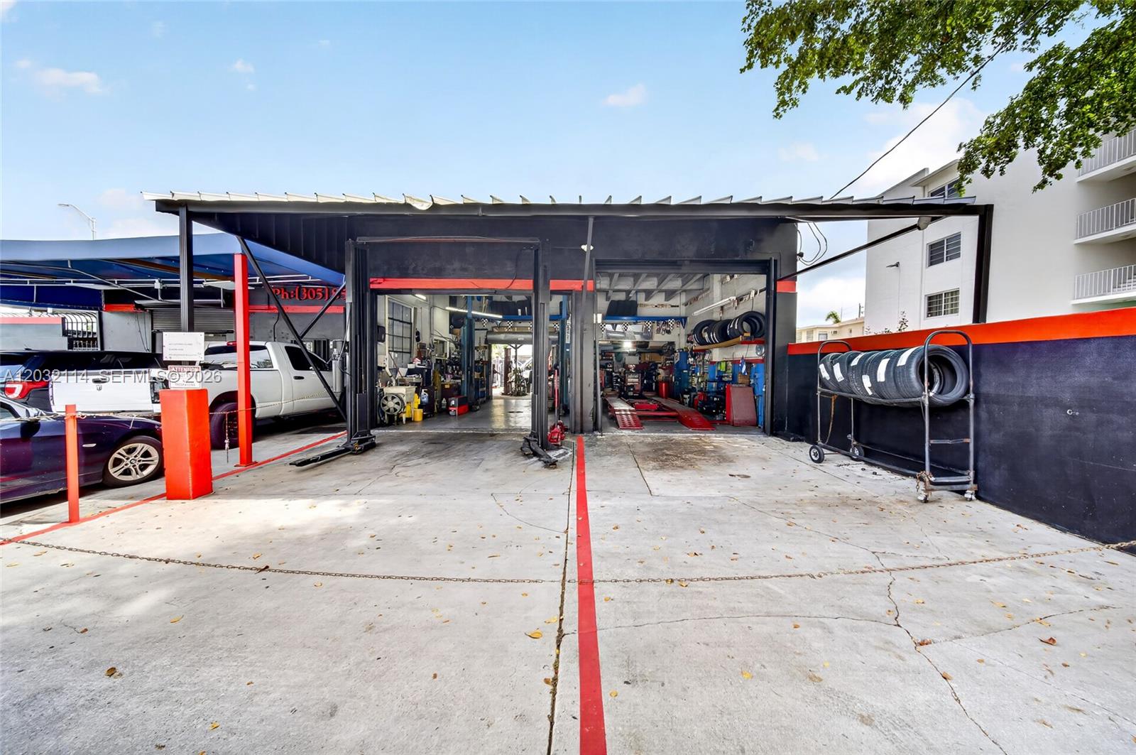 An exterior view of an automotive repair shop with two open service bays — MIAMI, FL