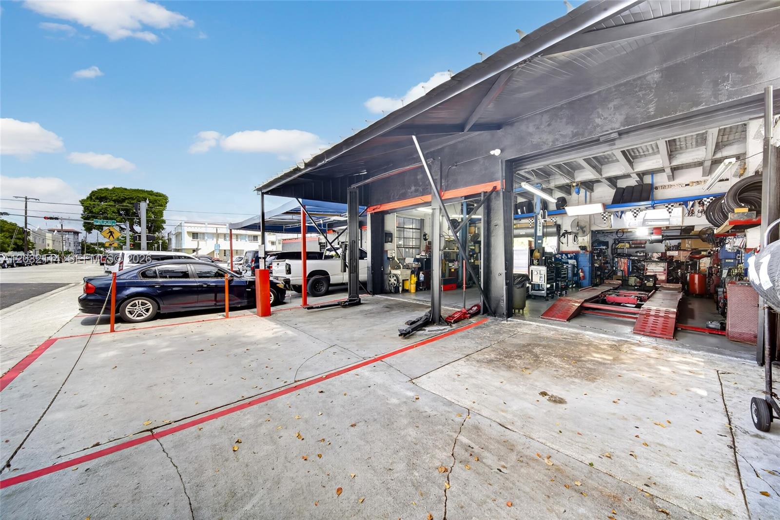 An exterior view of an automotive repair shop with service bays and parked vehicles — MIAMI, FL