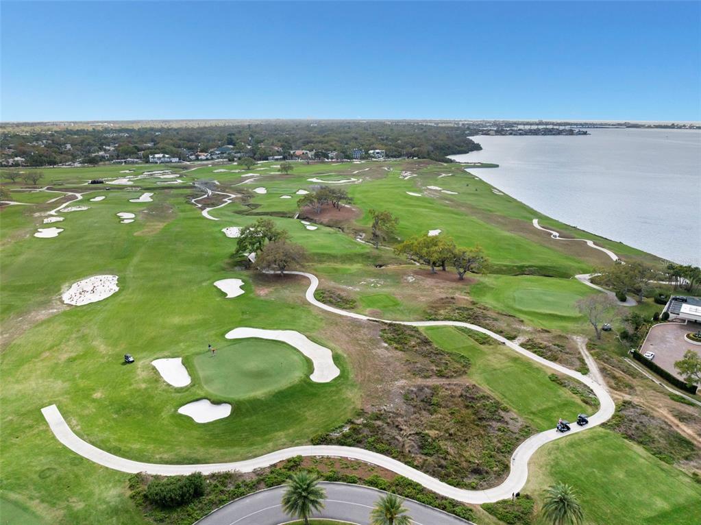 An aerial view of a golf course featuring sand bunkers, green fairways, and a large lake — 4 BELLEVIEW BOULEVARD UNIT 205, CLEARWATER, FL