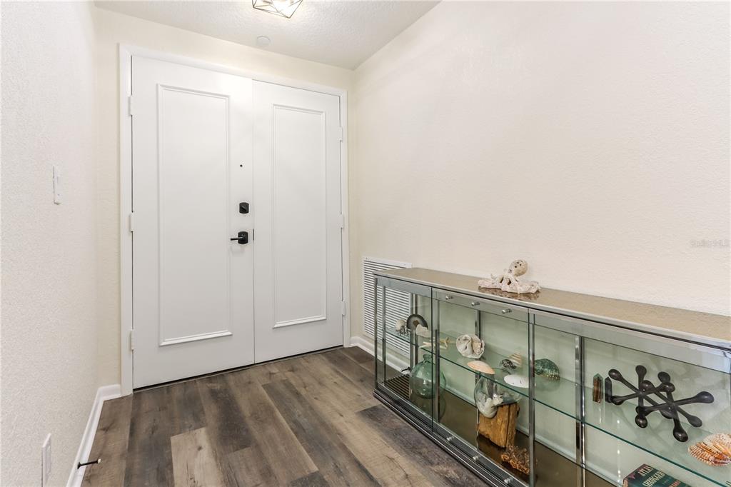 An entryway features white double doors, wood-look flooring, and a glass display console table — 4 BELLEVIEW BOULEVARD UNIT 205, CLEARWATER, FL