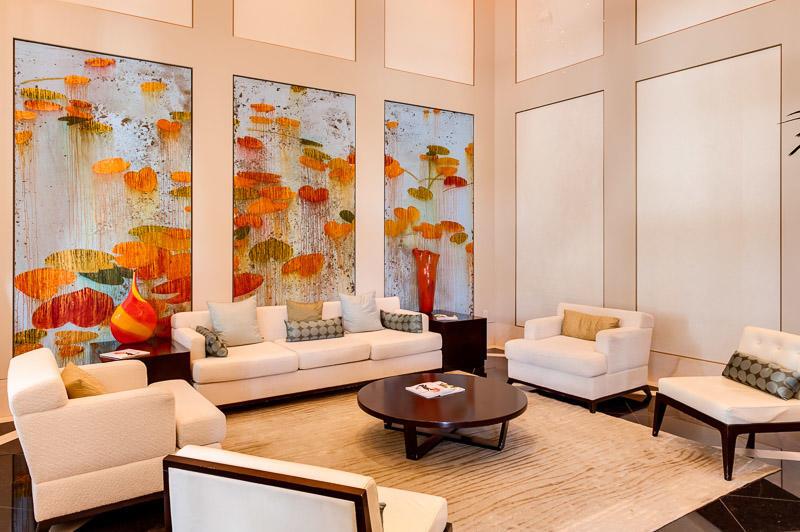 A living room features white furniture, a round coffee table, and three large floral artworks — 550 Okeechobee Boulevard # 604, West Palm Beach FL 33401, WEST PALM BEACH, FL
