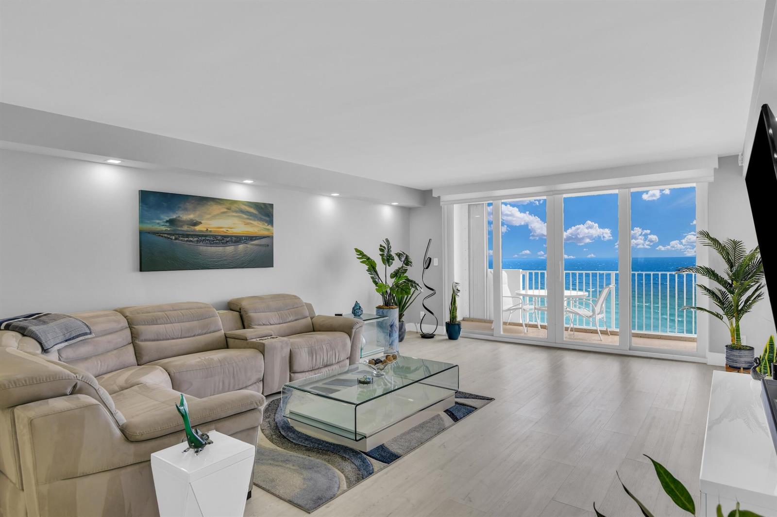 A living room with a beige sectional, glass coffee table, and sliding doors overlooking the ocean — 3000 S Ocean Boulevard # 1103, Boca Raton FL 33432, BOCA RATON, FL