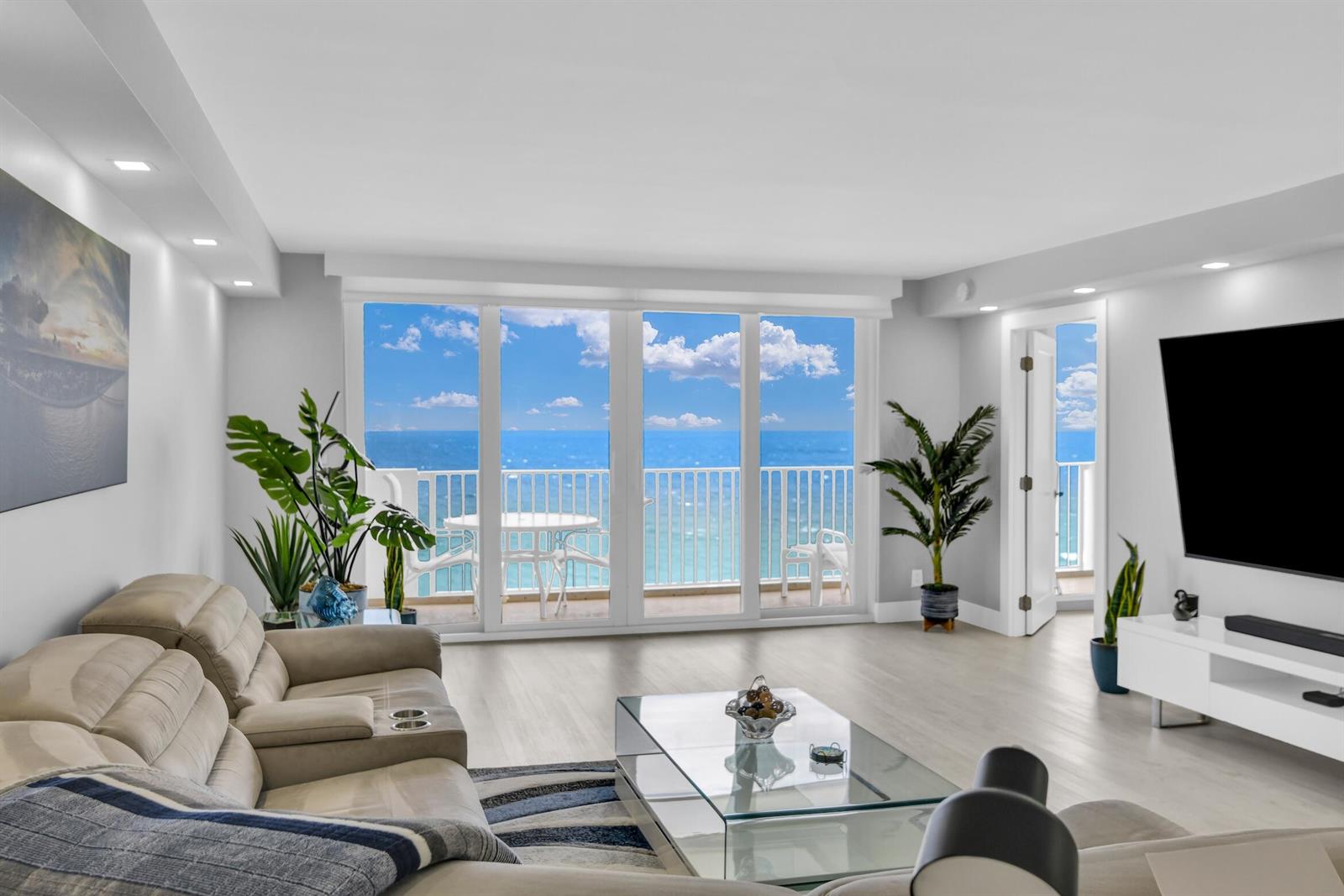 A living room features a beige sectional, glass coffee table, and sliding doors overlooking the ocean — 3000 S Ocean Boulevard # 1103, Boca Raton FL 33432, BOCA RATON, FL