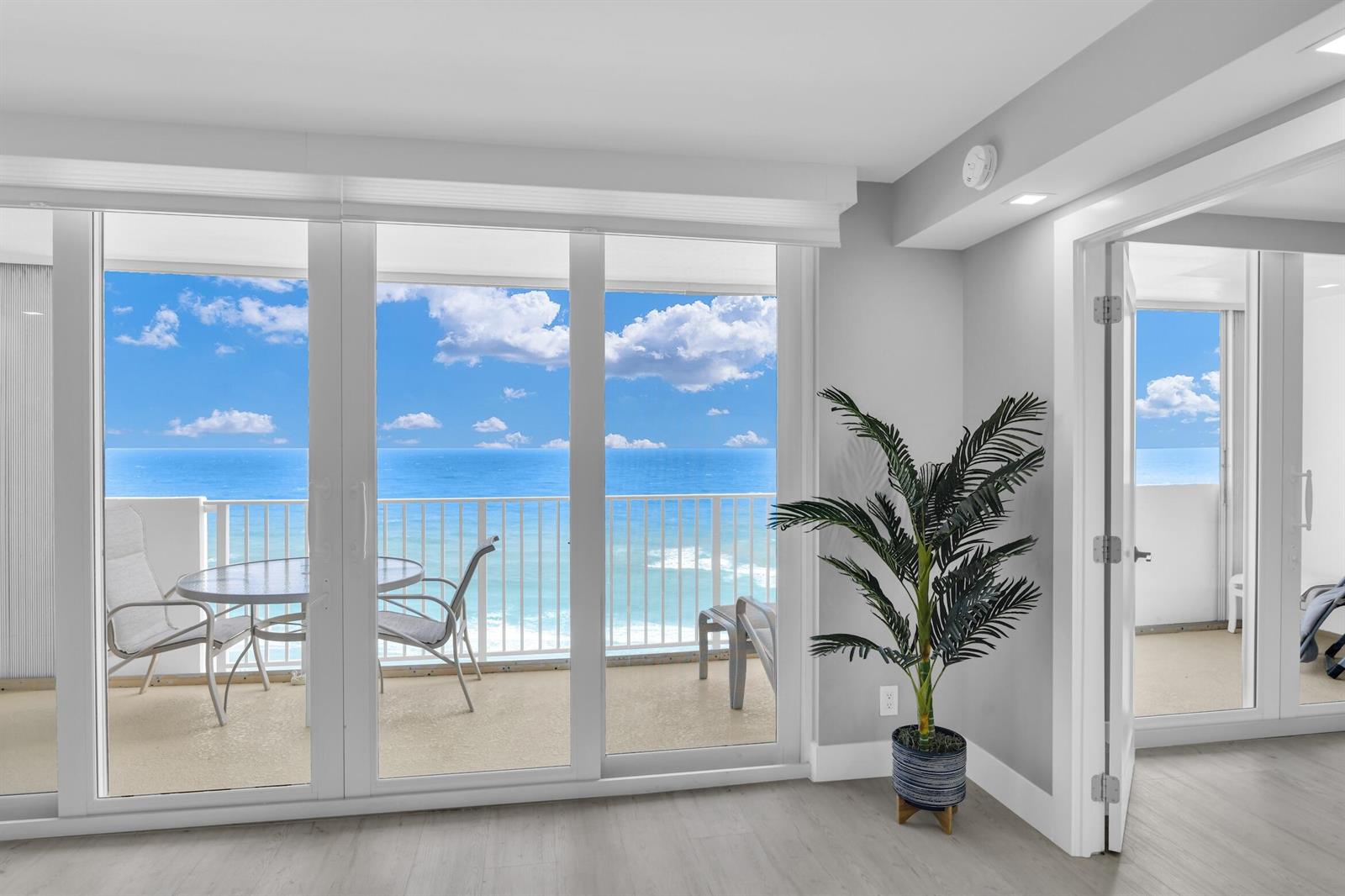 A room with light wood flooring and a potted plant overlooks a balcony with ocean views — 3000 S Ocean Boulevard # 1103, Boca Raton FL 33432, BOCA RATON, FL
