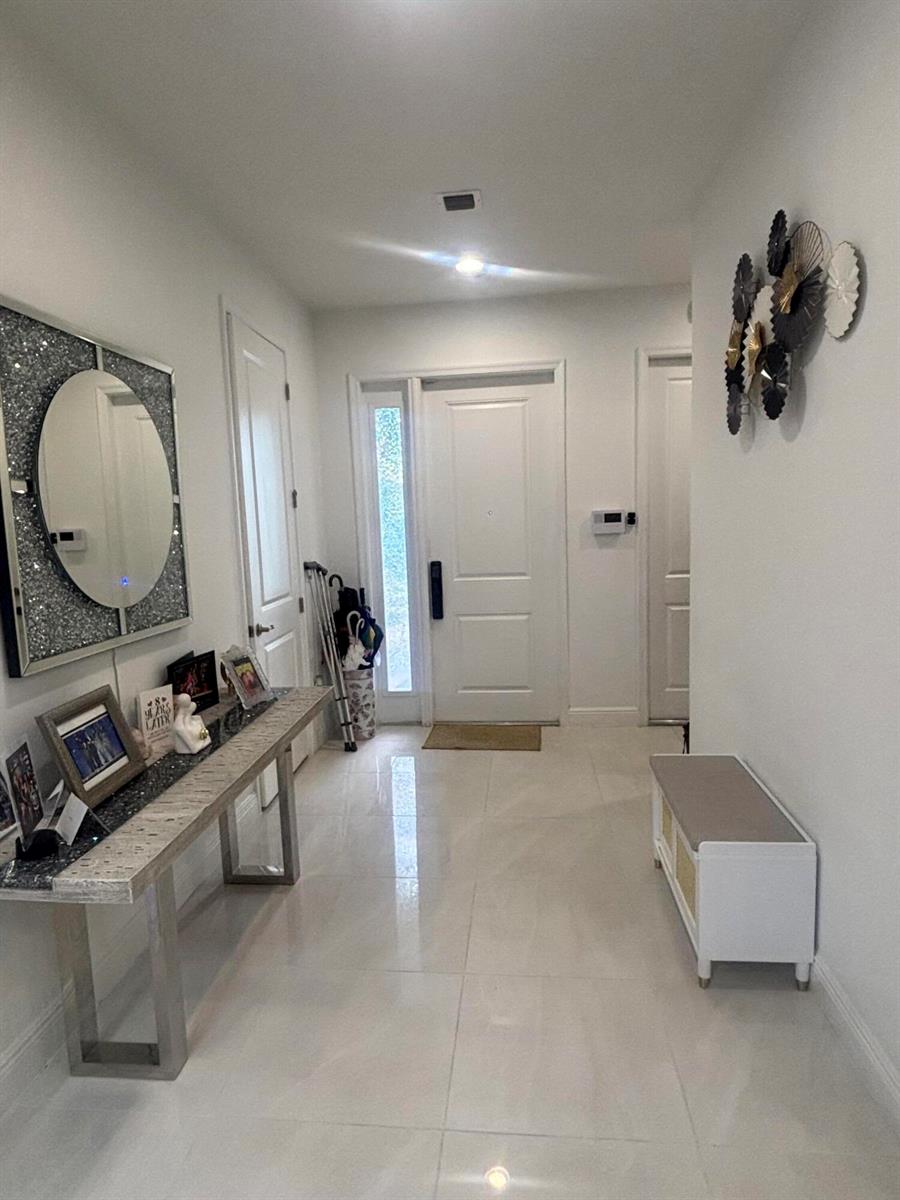 A bright entryway features a console table, a wall mirror, a bench, and tile flooring — 4834 Sand Dollar Drive, Westlake FL 33470, WESTLAKE, FL