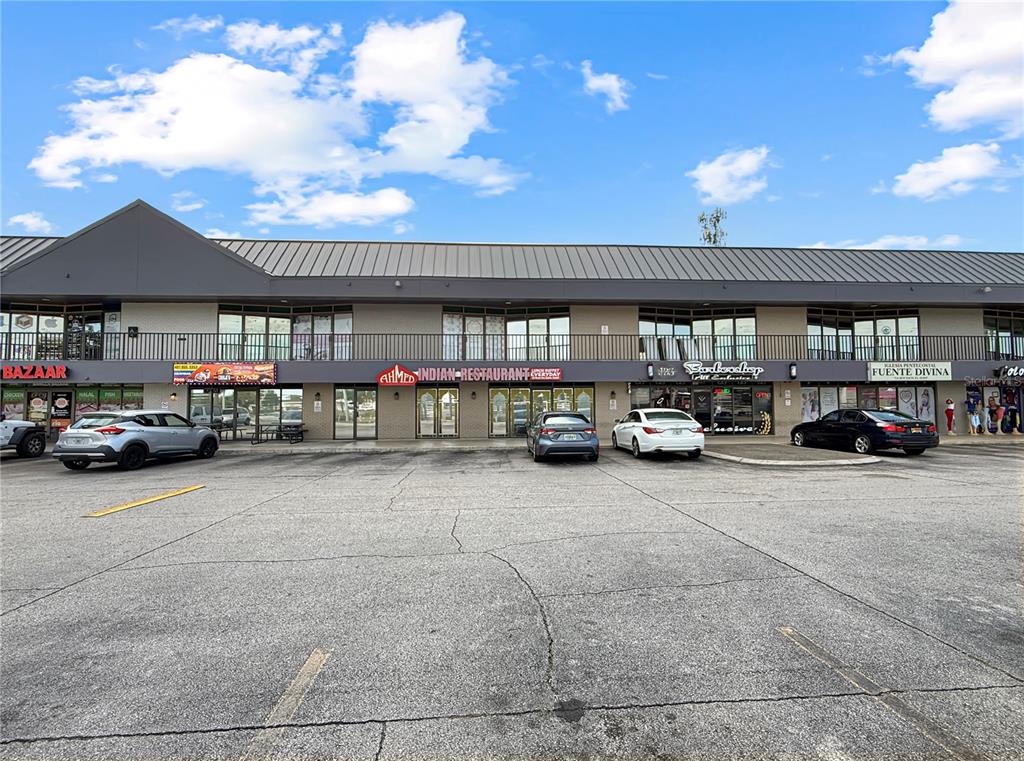 A commercial strip mall building with several storefronts and a large parking lot in front — 11301 S ORANGE BLOSSOM TRAIL UNIT 204, ORLANDO, FL