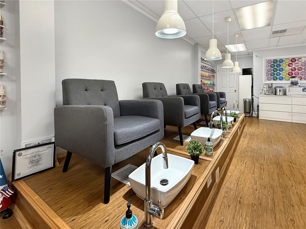 A nail salon features four gray armchairs positioned behind individual white pedicure basins on a platform — 11301 S ORANGE BLOSSOM TRAIL UNIT 204, ORLANDO, FL