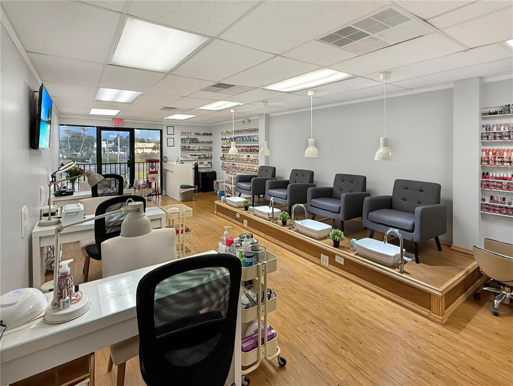 A nail salon features pedicure chairs on a raised platform, manicure stations, and wall-mounted polish racks — 11301 S ORANGE BLOSSOM TRAIL UNIT 204, ORLANDO, FL