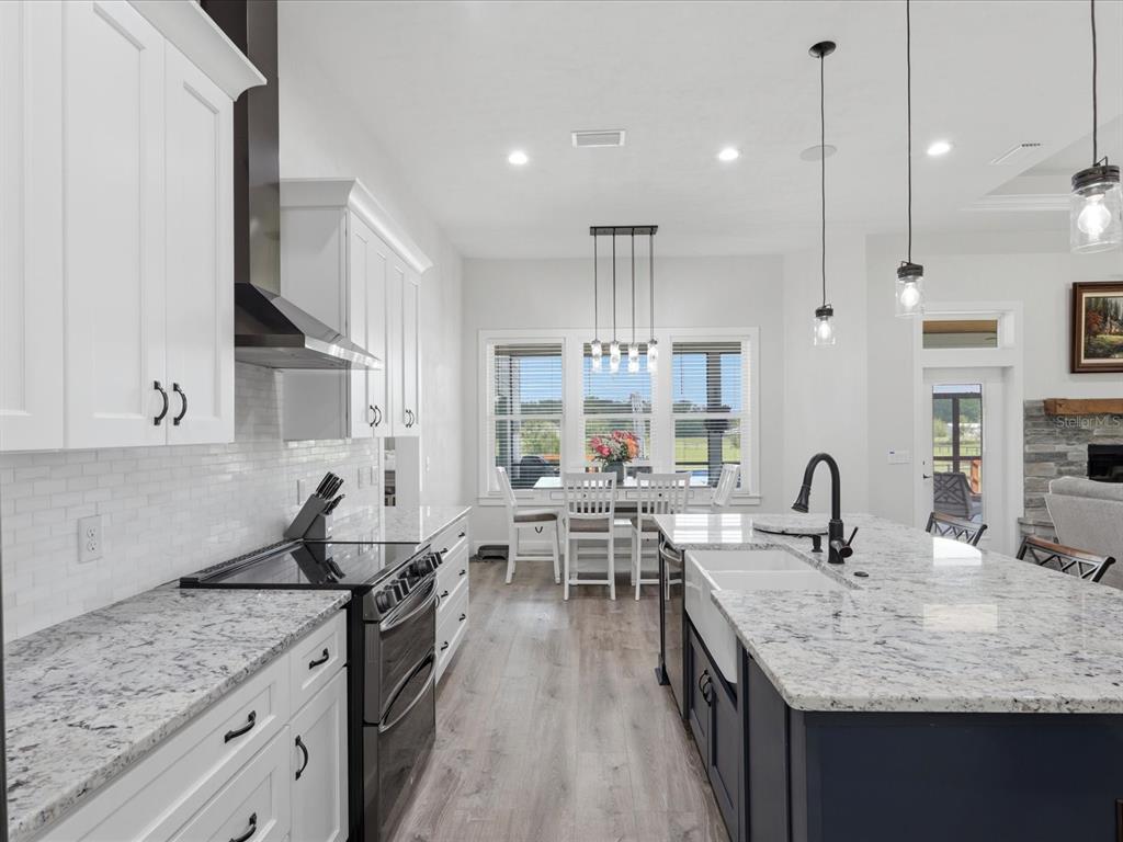 A kitchen with white cabinets, a dark blue island, granite countertops, and a dining area — 7311 NW 218TH STREET, ALACHUA, FL