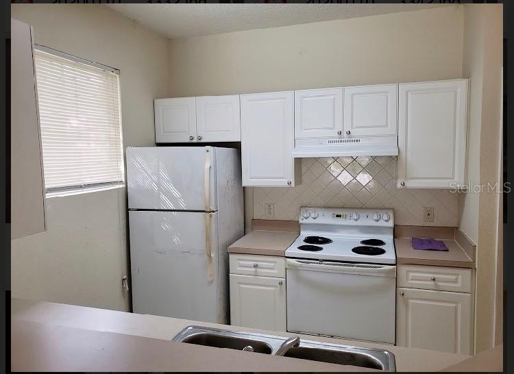 A kitchen features white cabinets, a white refrigerator, a white electric stove, and beige countertops — 18001 RICHMOND PLACE DRIVE UNIT 525, TAMPA, FL