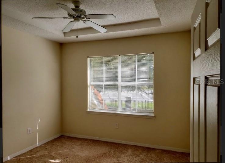 A bedroom with beige walls, tan carpet, a ceiling fan, and a window with blinds — 18001 RICHMOND PLACE DRIVE UNIT 525, TAMPA, FL