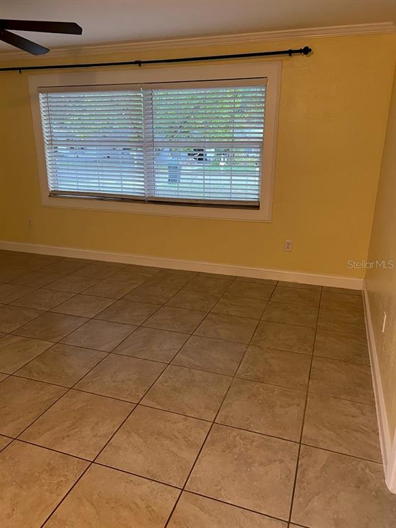 A room with yellow walls, tile flooring, and a large window with white blinds — 818 SCOTLAND STREET, DUNEDIN, FL