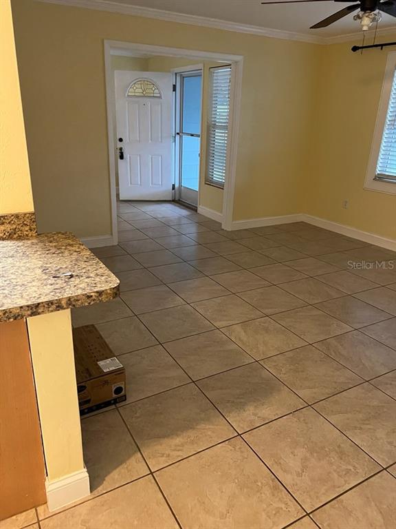 A room with beige tile flooring, yellow walls, and an open doorway leading outside — 818 SCOTLAND STREET, DUNEDIN, FL