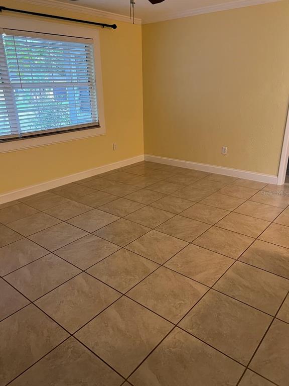 An empty room features yellow walls, large square floor tiles, and a window with blinds — 818 SCOTLAND STREET, DUNEDIN, FL
