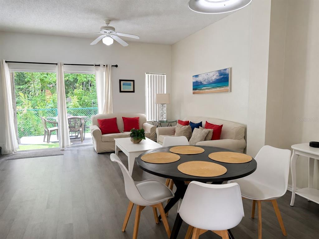 A living and dining area features a round table, white chairs, and a sliding glass door — 1119 PARK RIDGE CIRCLE, KISSIMMEE, FL