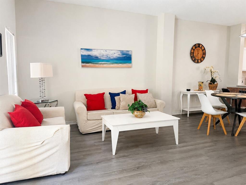 A living room features light-colored sofas, a white coffee table, and gray wood-look flooring — 1119 PARK RIDGE CIRCLE, KISSIMMEE, FL