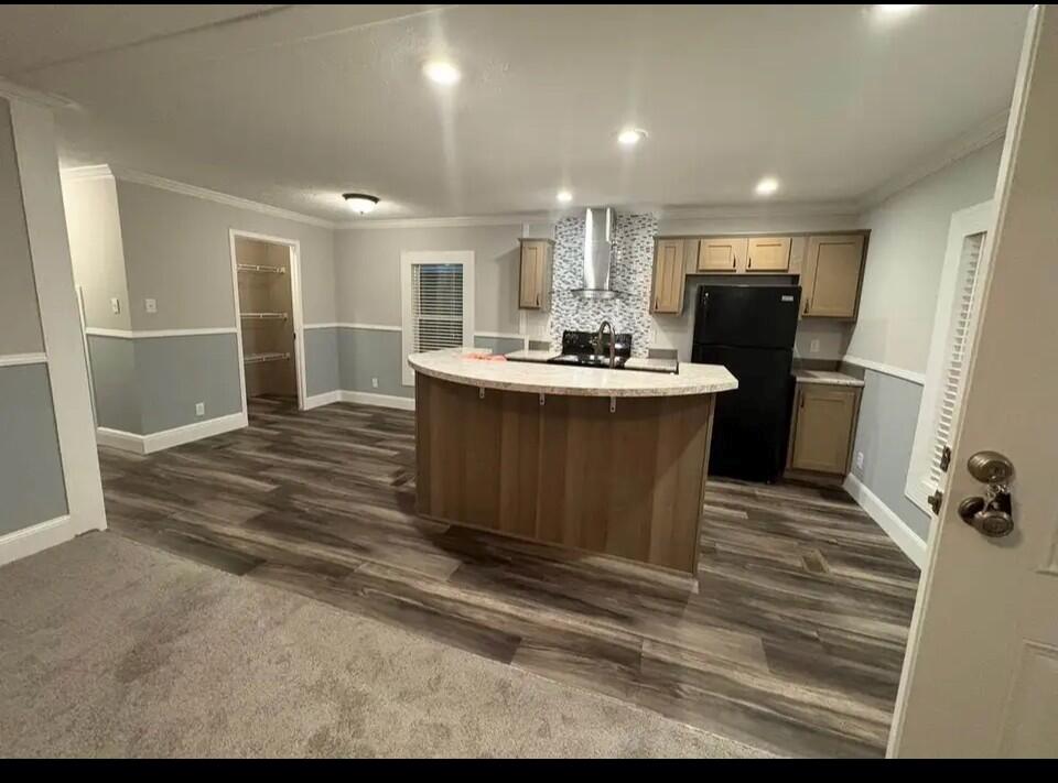 A kitchen with wood cabinets, a curved island, black appliances, and gray wood-look flooring — 76 Sandhill Boulevard, Fort Pierce FL 34982, FORT PIERCE, FL