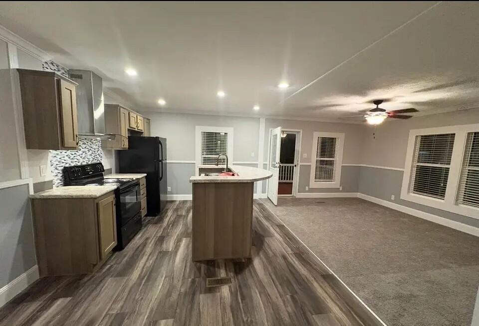 An open-concept kitchen and living area featuring wood-look flooring, gray walls, and a center island — 76 Sandhill Boulevard, Fort Pierce FL 34982, FORT PIERCE, FL