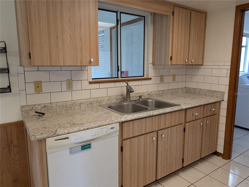 A kitchen features wood-grain cabinets, a granite countertop, a double sink, and white subway tile — 10881 SW 78TH COURT, OCALA, FL